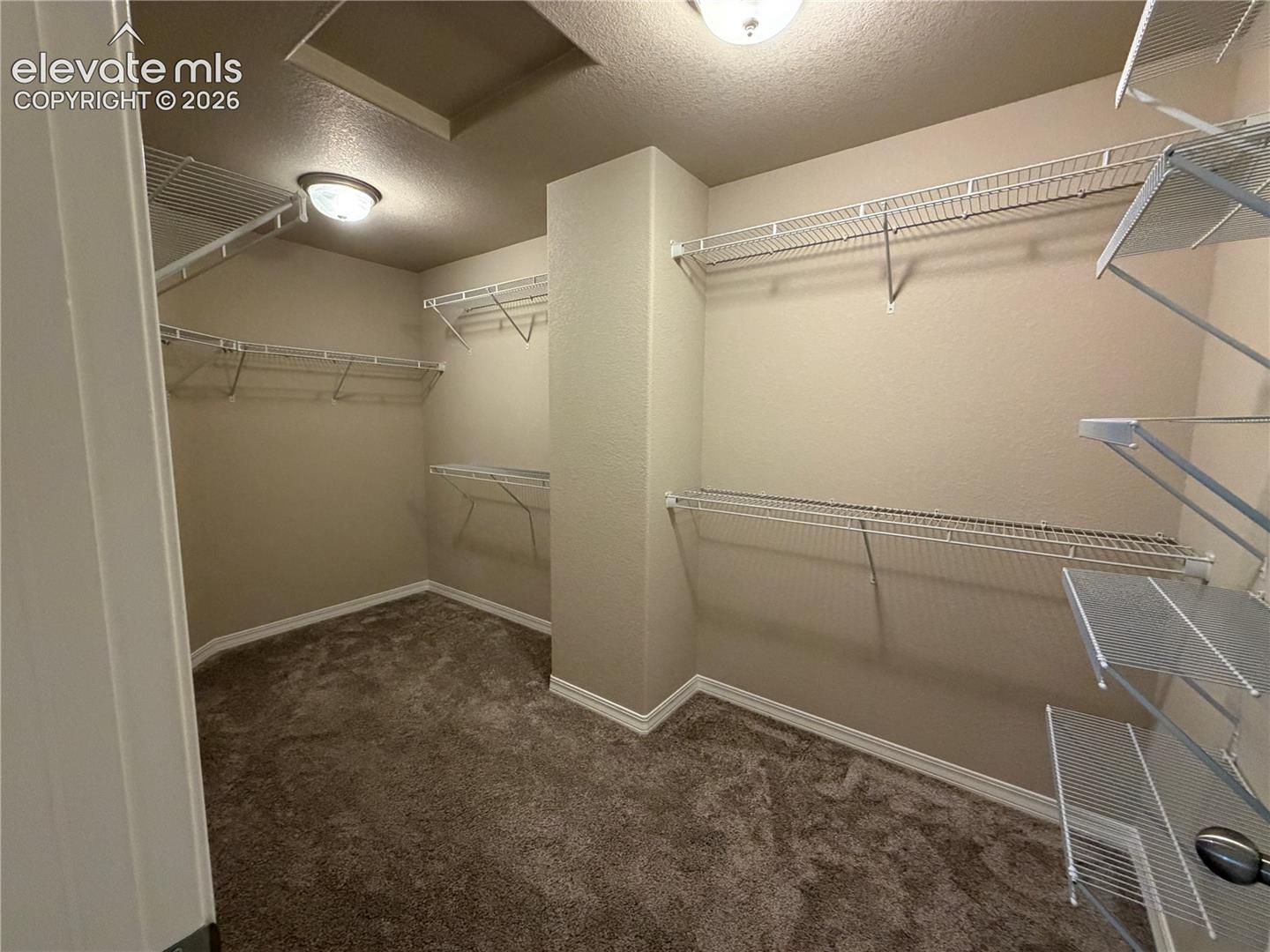 Spacious closet with integrated wire shelving systems and warm neutral wall tones