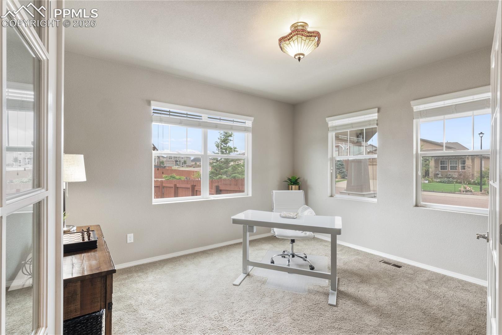 Home office with light colored carpet and plenty of natural light