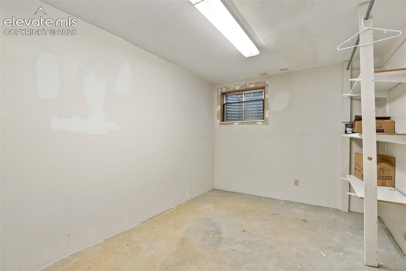 Interior room featuring an inset window with a protective well, built-in shelving unit, and overhead lighting