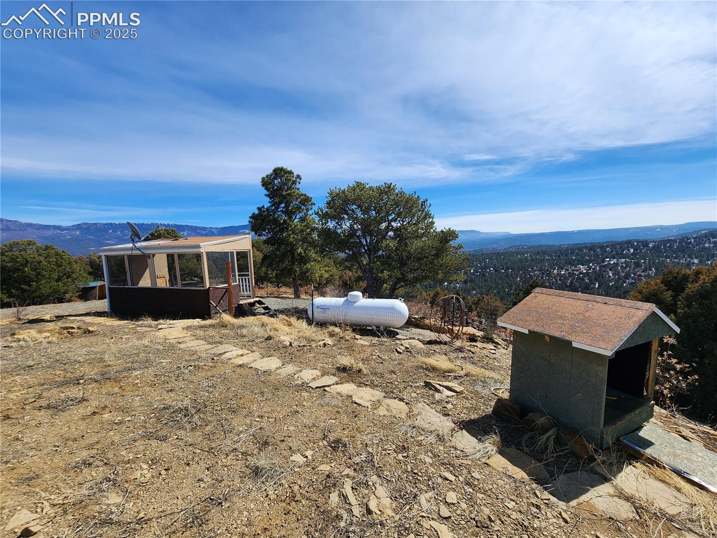 View of yard featuring a sunroom, a mountain view, an outdoor structure, and exterior structure