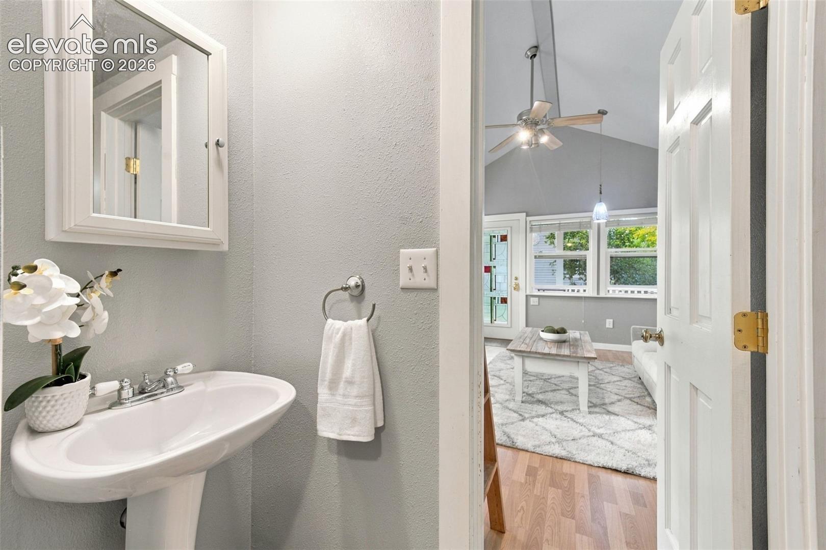 Powder room featuring a white pedestal sink, framed medicine cabinet, and brushed metal towel ring