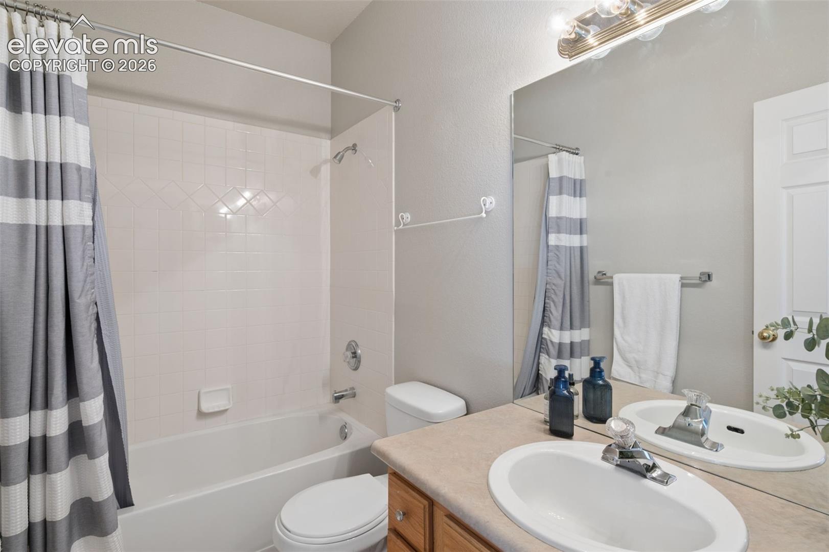 Full bathroom featuring a tub-shower combination with tile surround, vanity with an integrated oval sink, and a large wall-mounted mirror with an overhead light fixture
