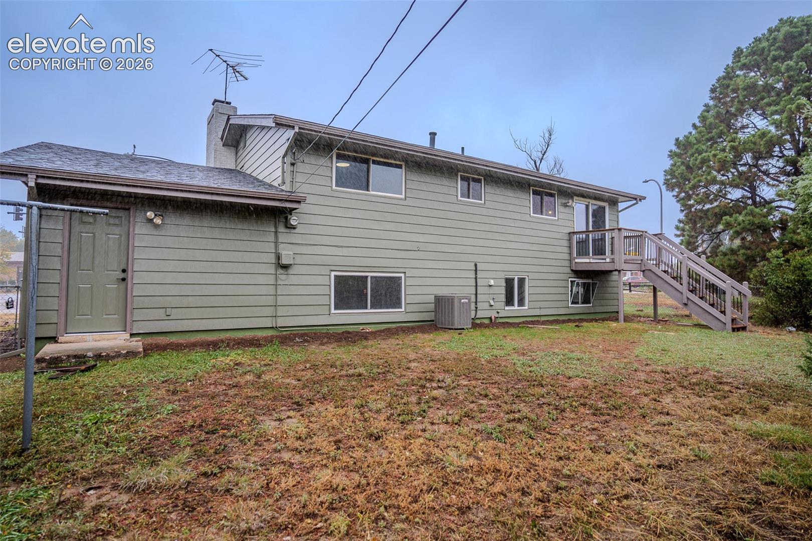 Horizontal lap siding exterior featuring a raised wooden deck with stairs, a chimney, and multiple windows