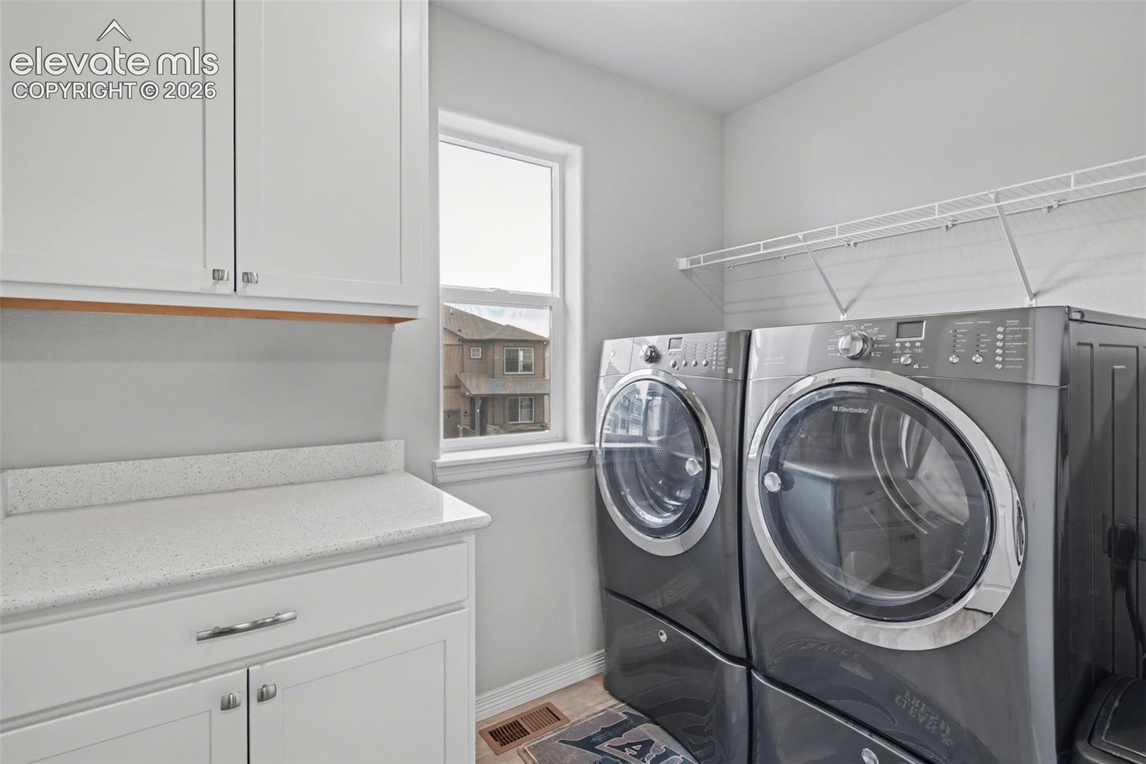 White cabinetry with chrome hardware, light-toned countertop, and window