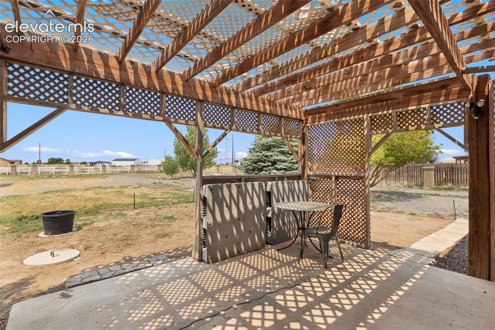 Covered patio featuring a wood-beam pergola with lattice screening and a concrete floor