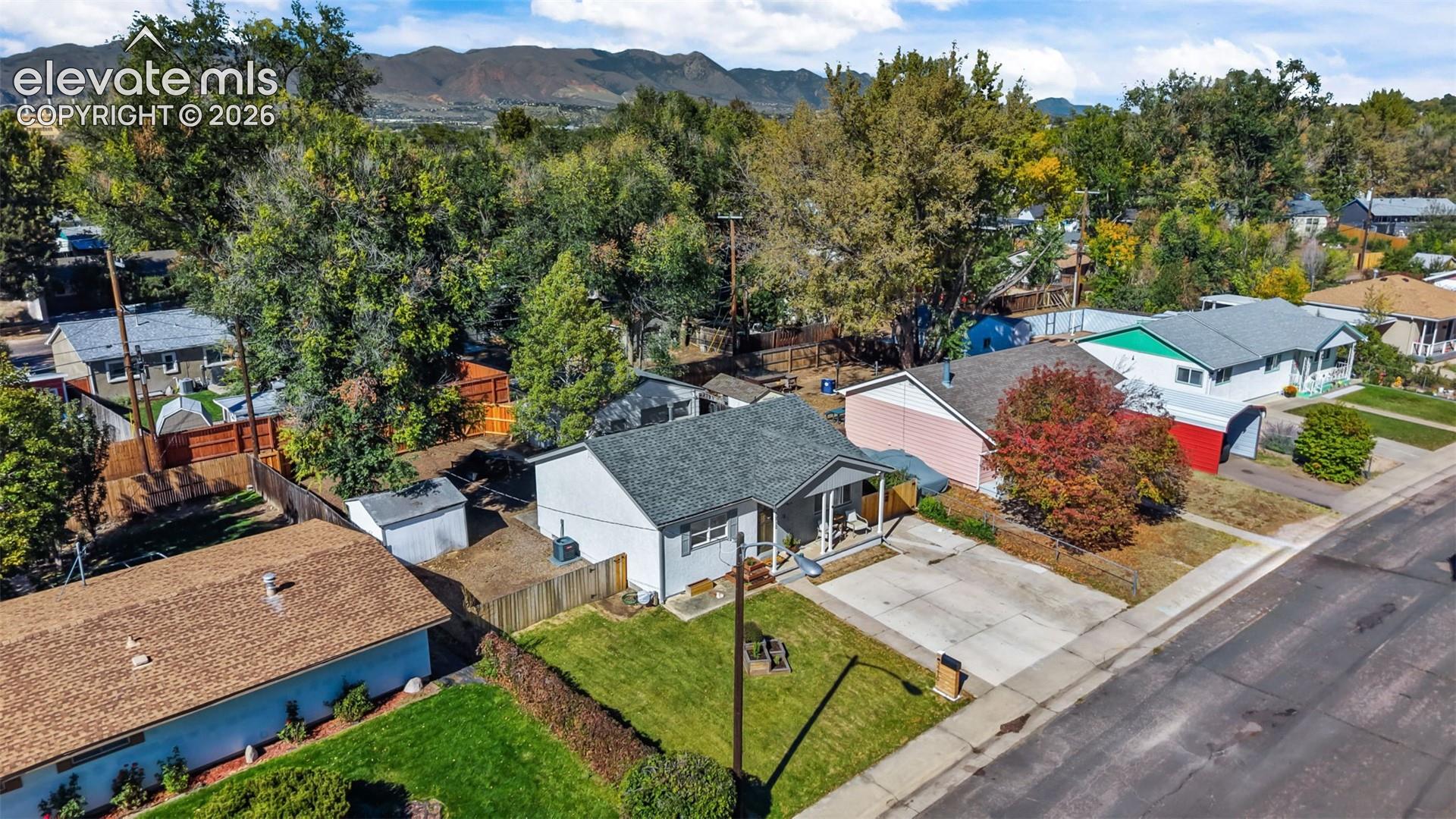 Single-story residence featuring a shingled roof, concrete driveway, front lawn, and wood fencing