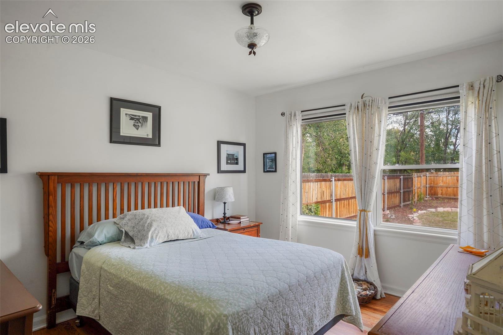 Rear bedroom with large windows and hardwood flooring