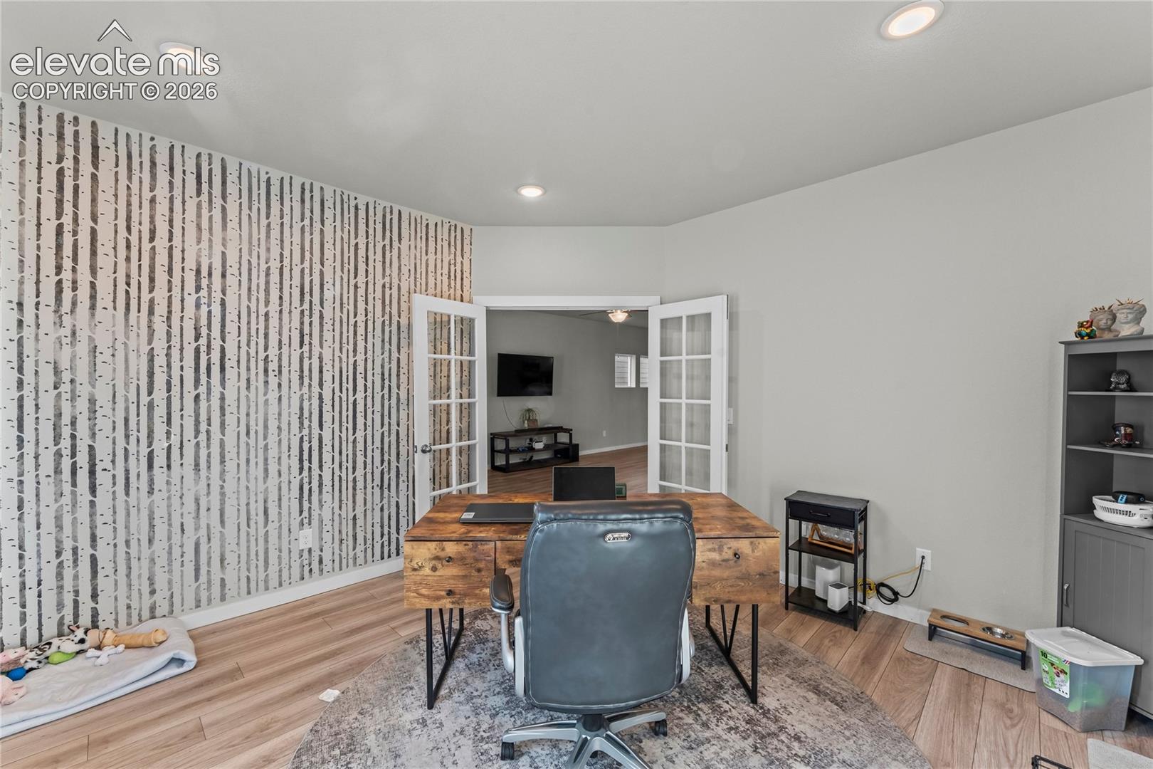 Recessed lighting, wood-finish flooring, accent wall, French doors, built-in shelving