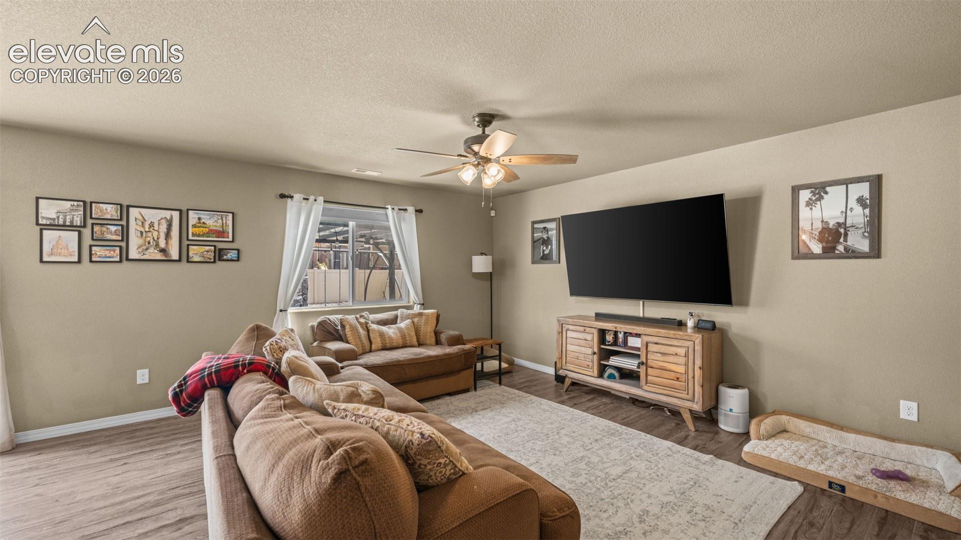 Living area with wood-finish flooring, neutral wall tones, and a ceiling fan