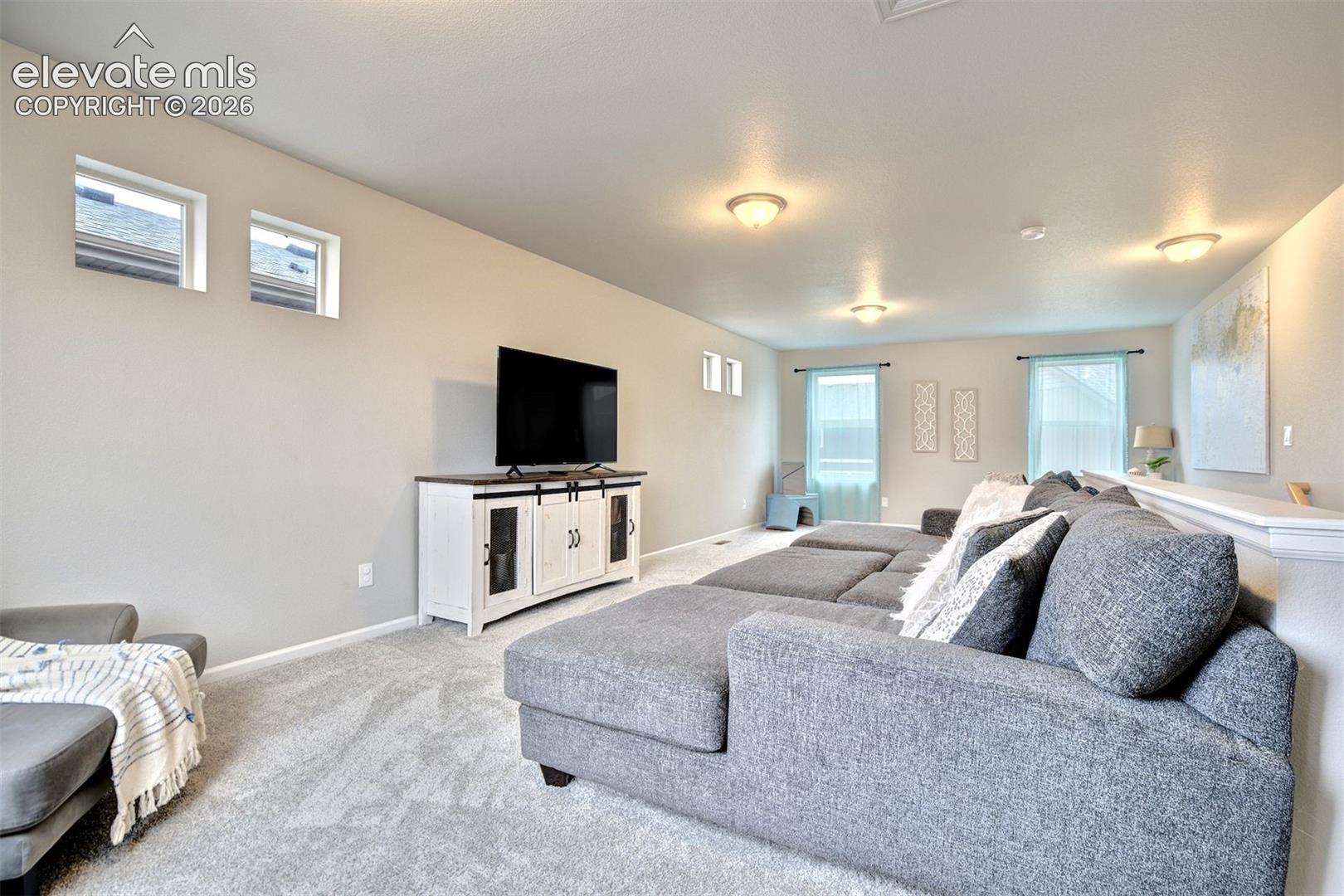 Expansive room featuring neutral wall tones, plush carpeting, recessed ceiling lighting, and multiple windows providing natural illumination