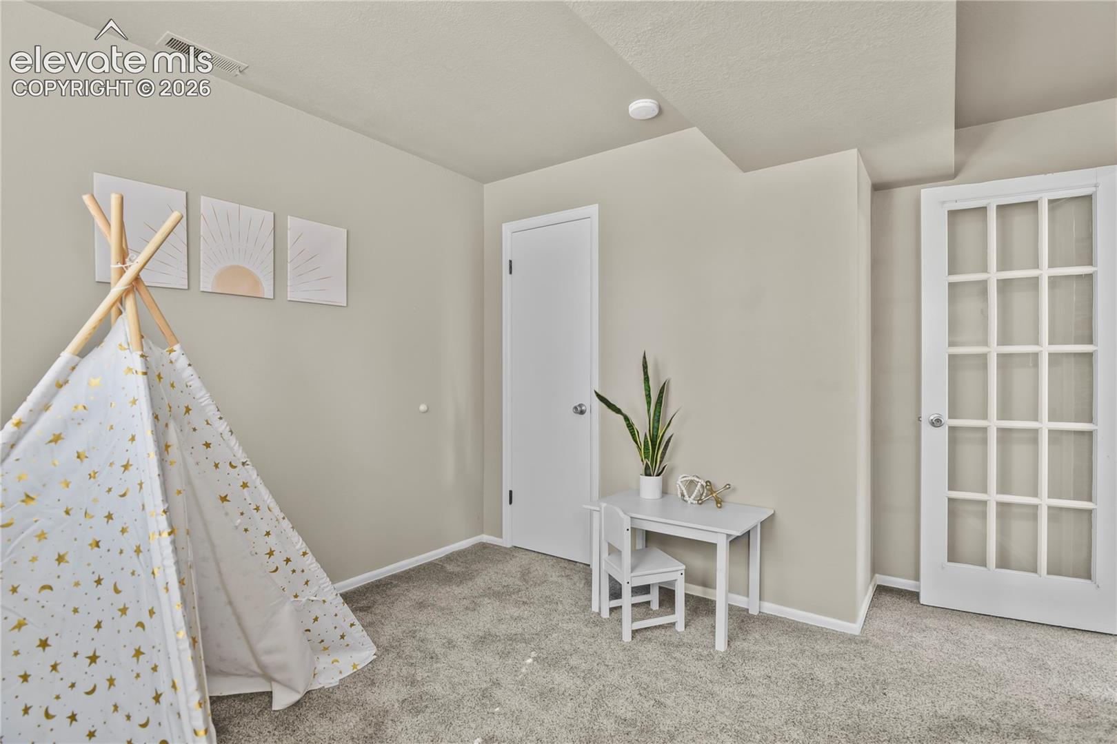 Room featuring neutral wall tones, wall-to-wall carpeting, and a white French door with glass panes