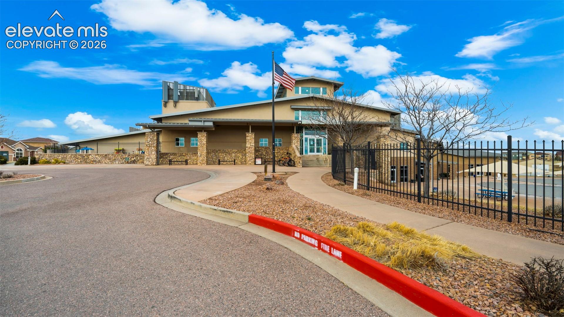 Stone facade building with a curved driveway, paved walkway, and landscaping