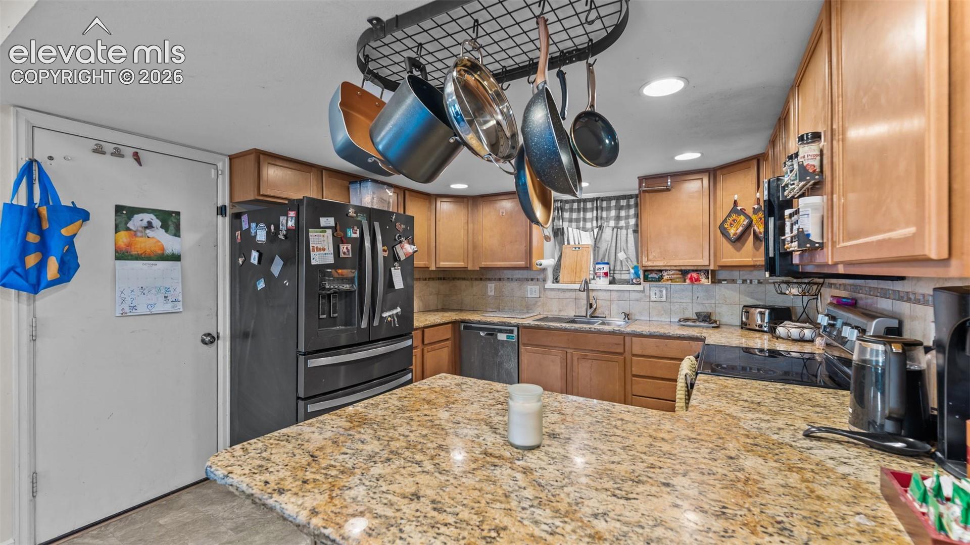 Kitchen featuring natural wood cabinetry, stone countertops, an integrated ceiling-mounted pot rack, recessed lighting, and a stainless steel built-in dishwasher