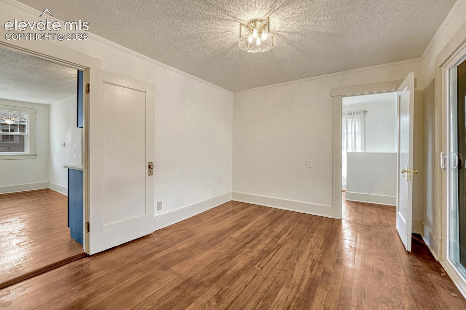 Wood-finish flooring throughout, white trim, crown molding, and a modern semi-flush mount ceiling fixture