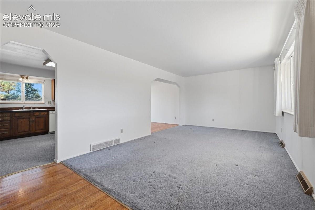 Living area featuring neutral wall tones, wall-to-wall carpeting, and an arched entryway