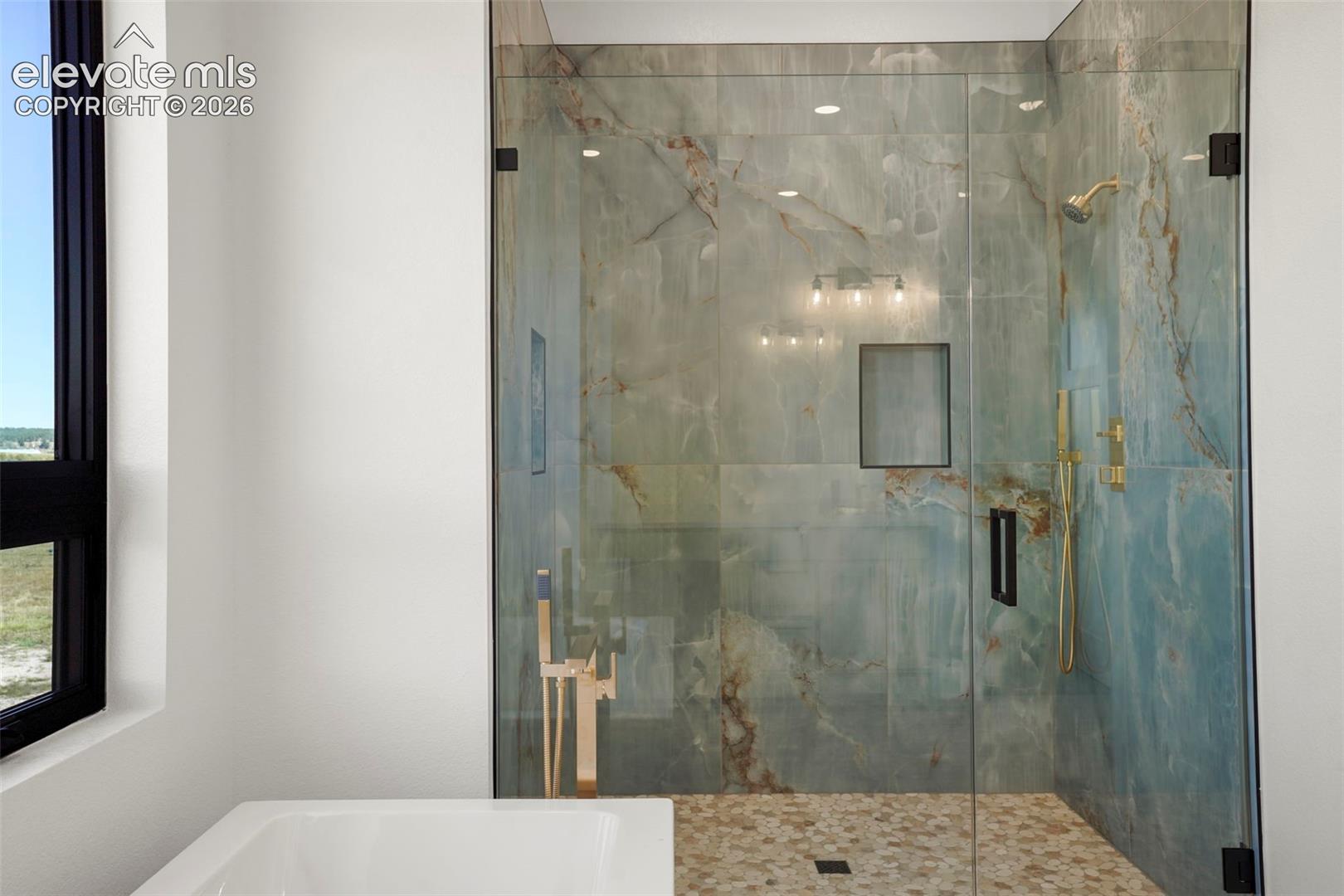 Walk-in shower with clear glass enclosure and stone-look tile