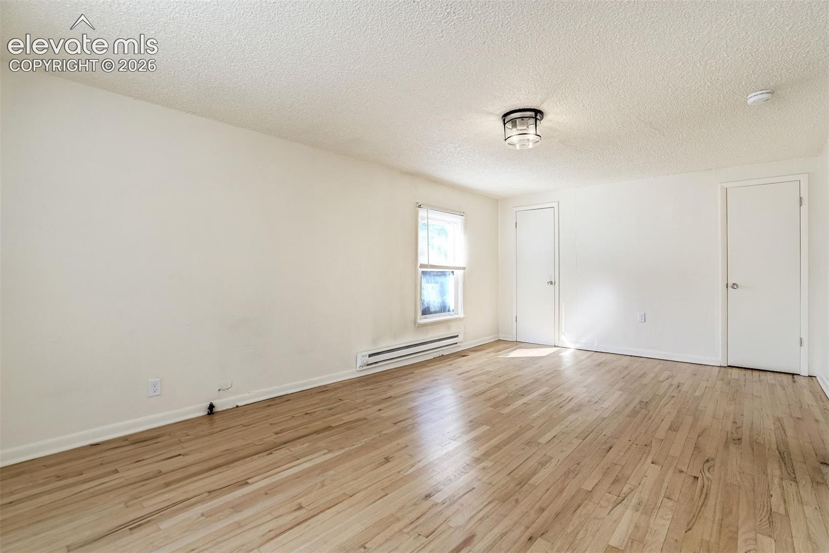 Interior space featuring wood-finish flooring, a flush-mount ceiling light fixture, a single window, and two interior doors