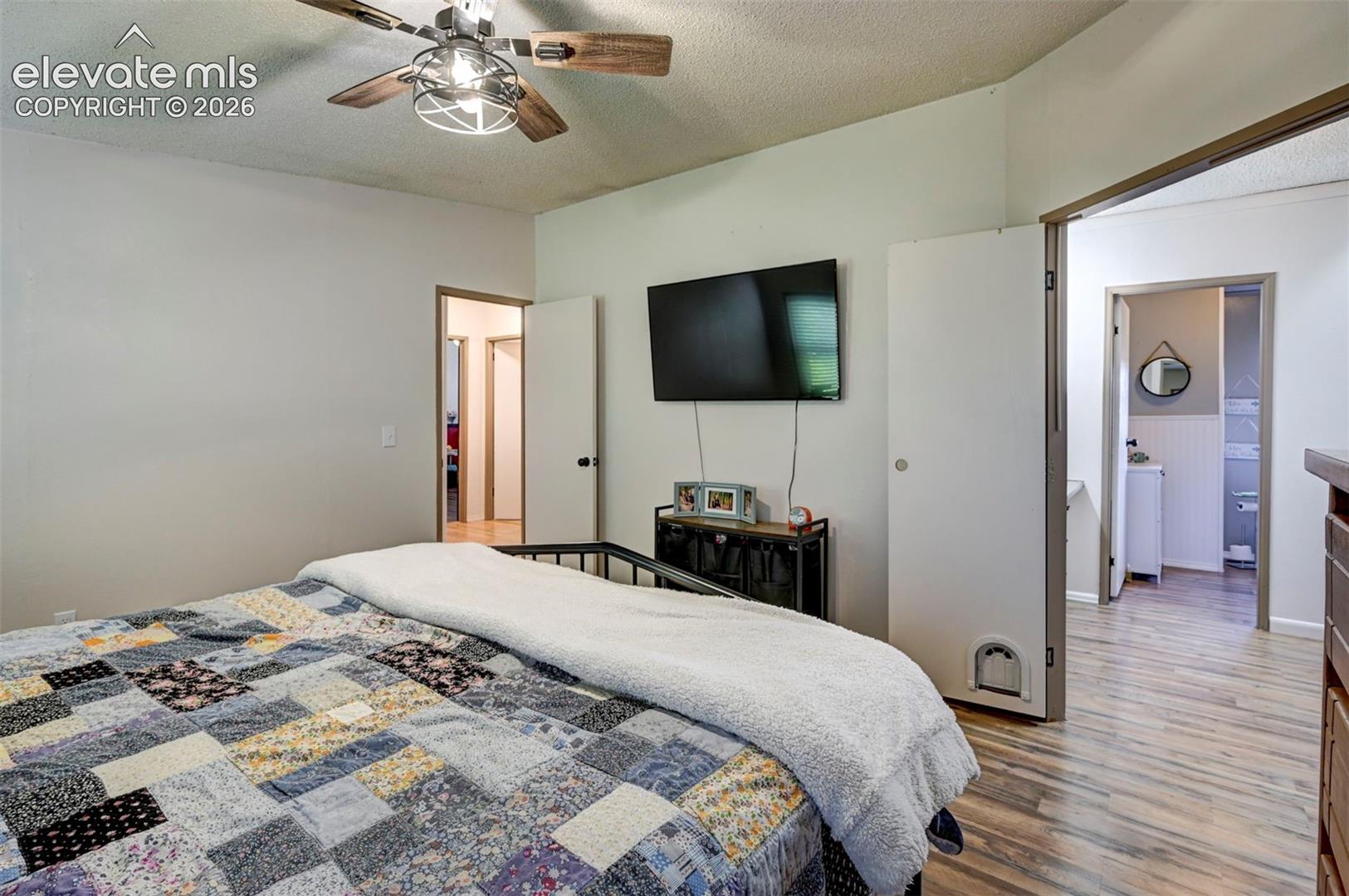 Bedroom with a textured ceiling, light wood finished floors, and ceiling fan