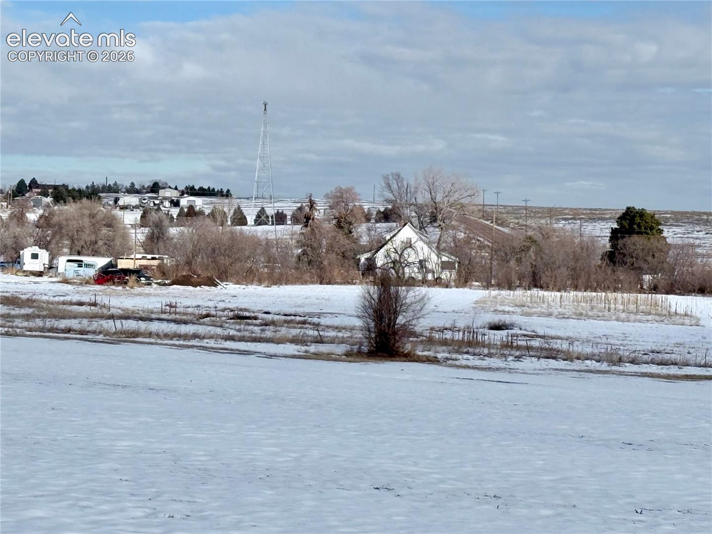 Expansive acreage featuring mature trees, open terrain, and a white exterior structure