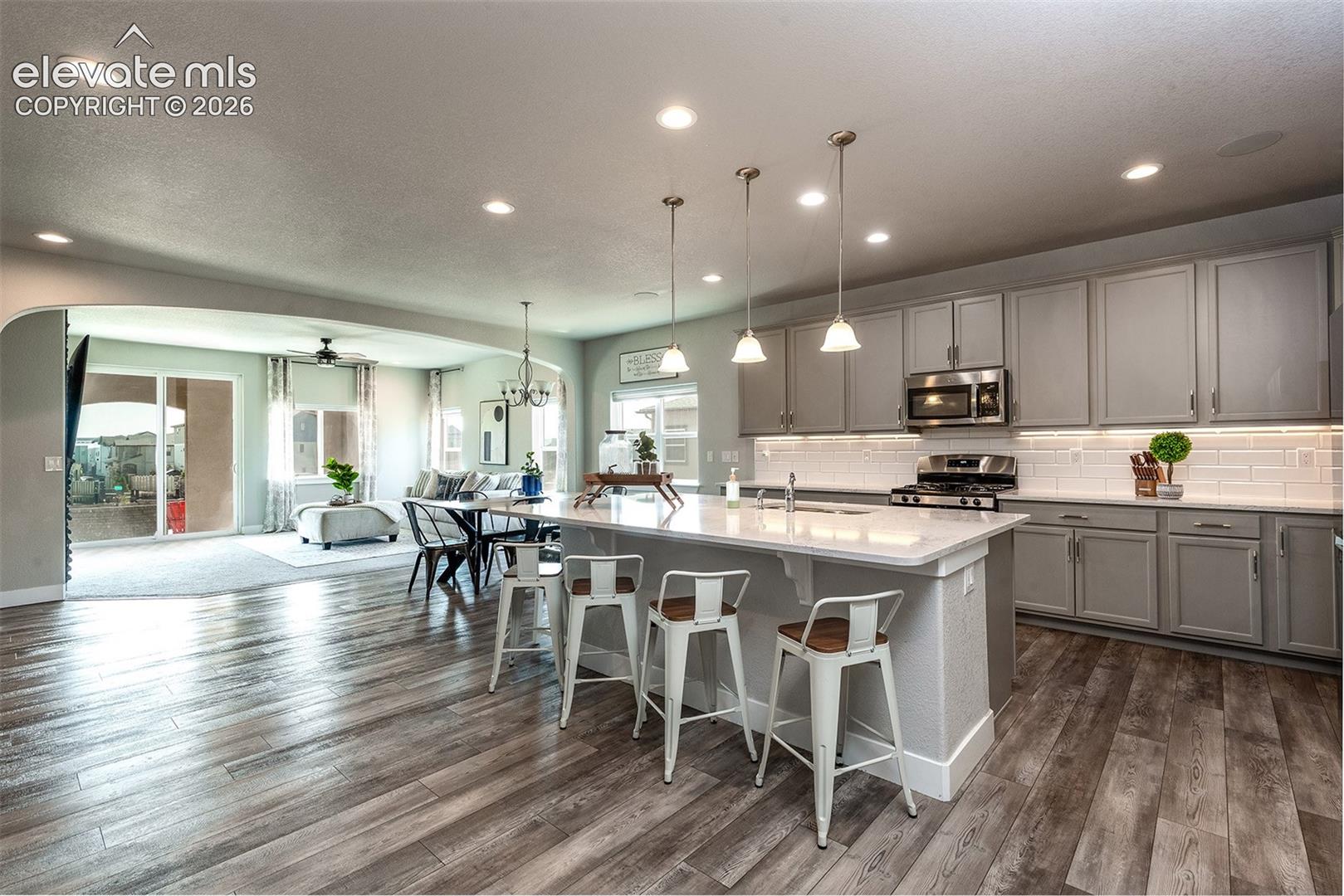 Kitchen featuring a center island with pendant lighting, gray cabinetry, stainless steel appliances, and wood-finish flooring