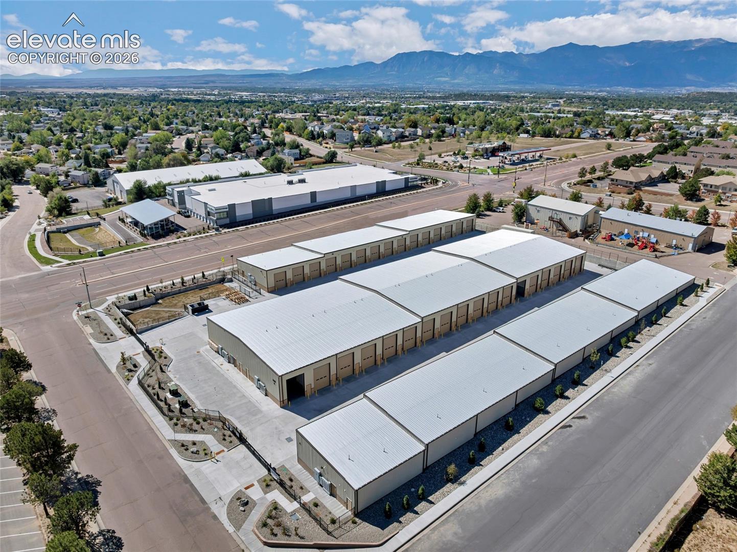 Multiple storage buildings featuring roll-up doors, extensive paved access, and a perimeter fence