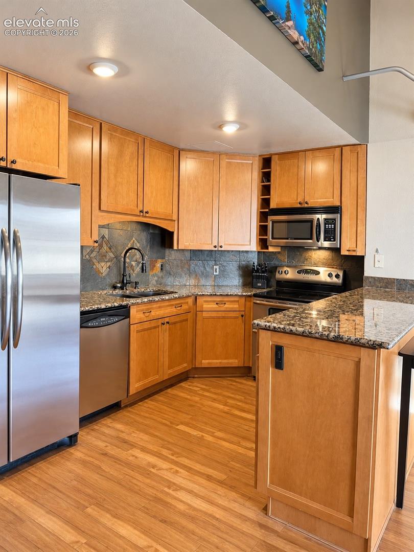 Kitchen with wood-finish flooring, recessed lighting, and stainless steel appliances