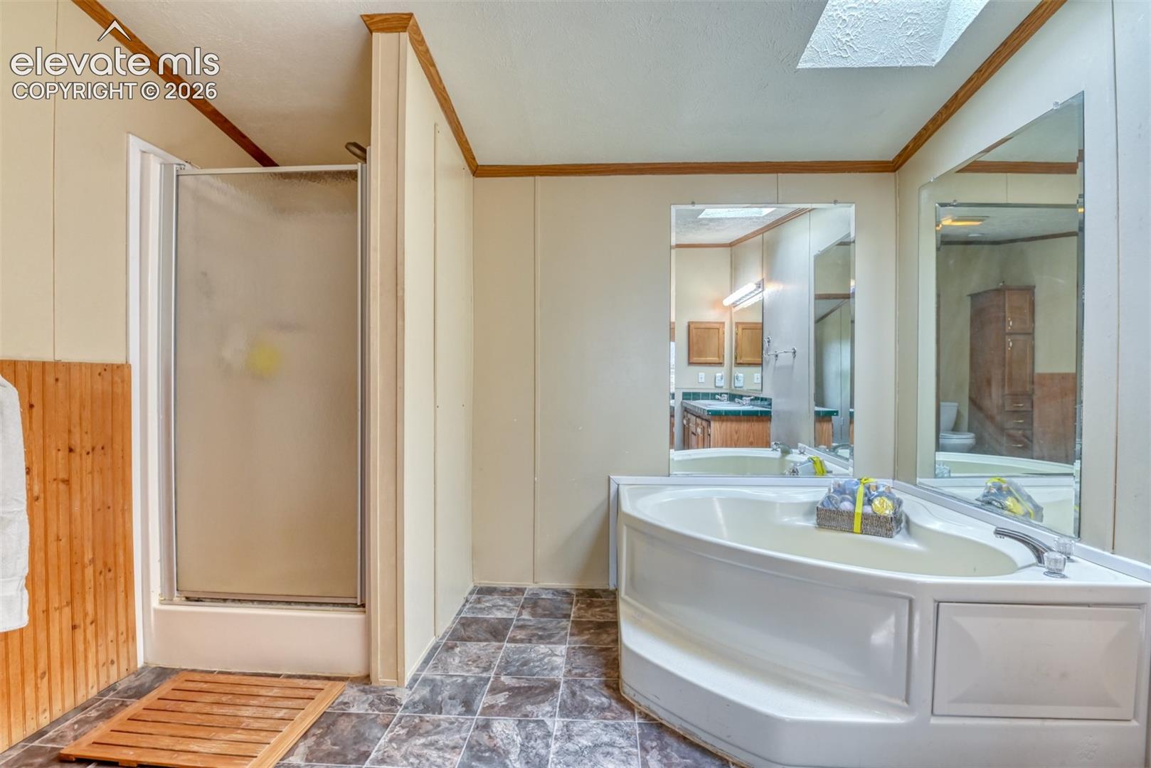 Bathroom featuring a corner soaking tub, separate enclosed shower, and patterned tile flooring