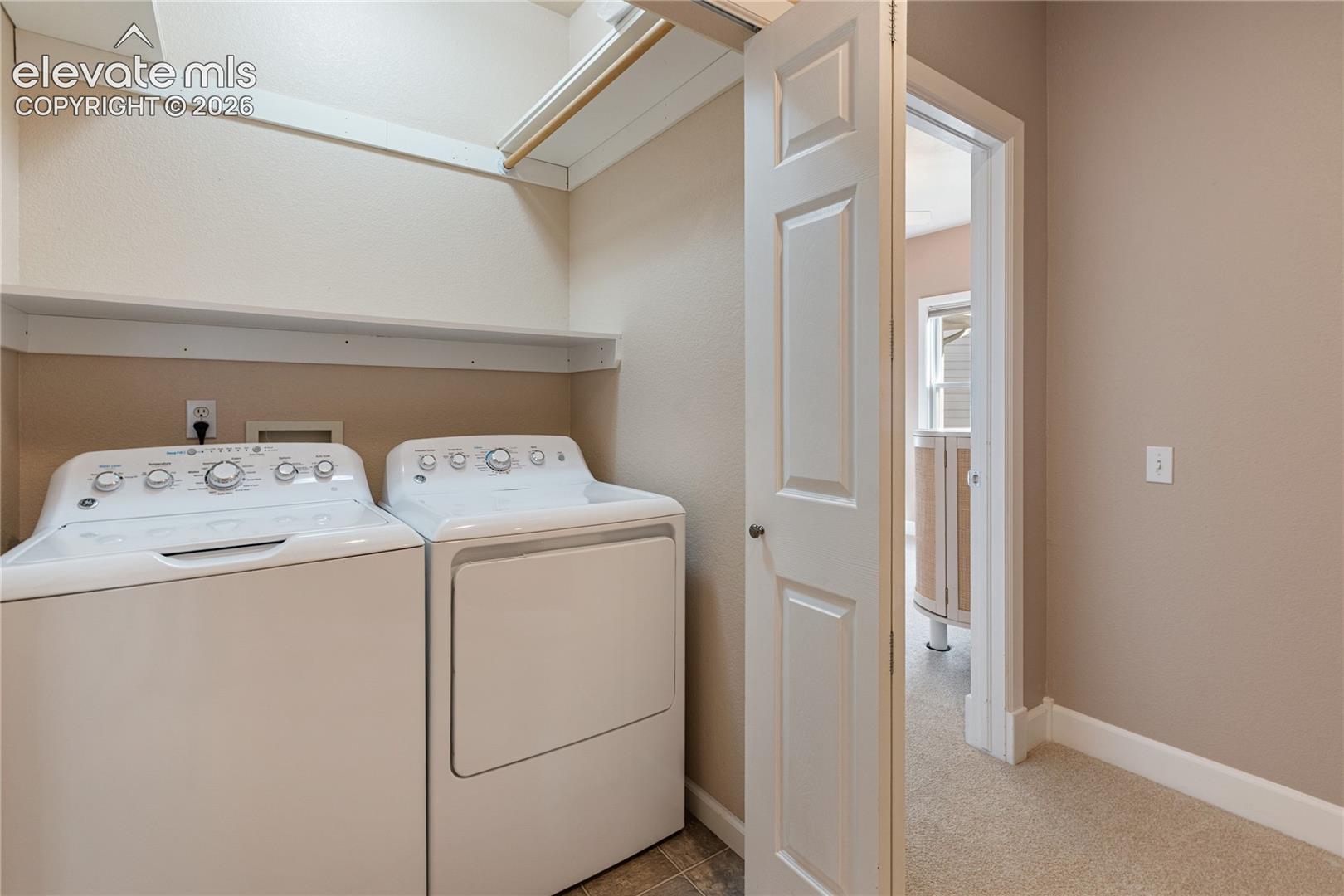 Dedicated laundry area featuring a shelf, hanging rod, and tile flooring