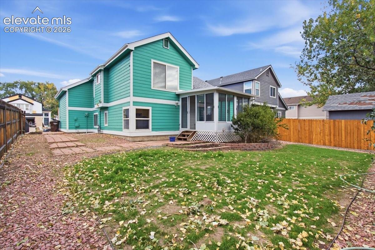 Exterior features include horizontal lap siding, a screened-in porch with latticework base, a stone paver walkway, and a perimeter privacy fence