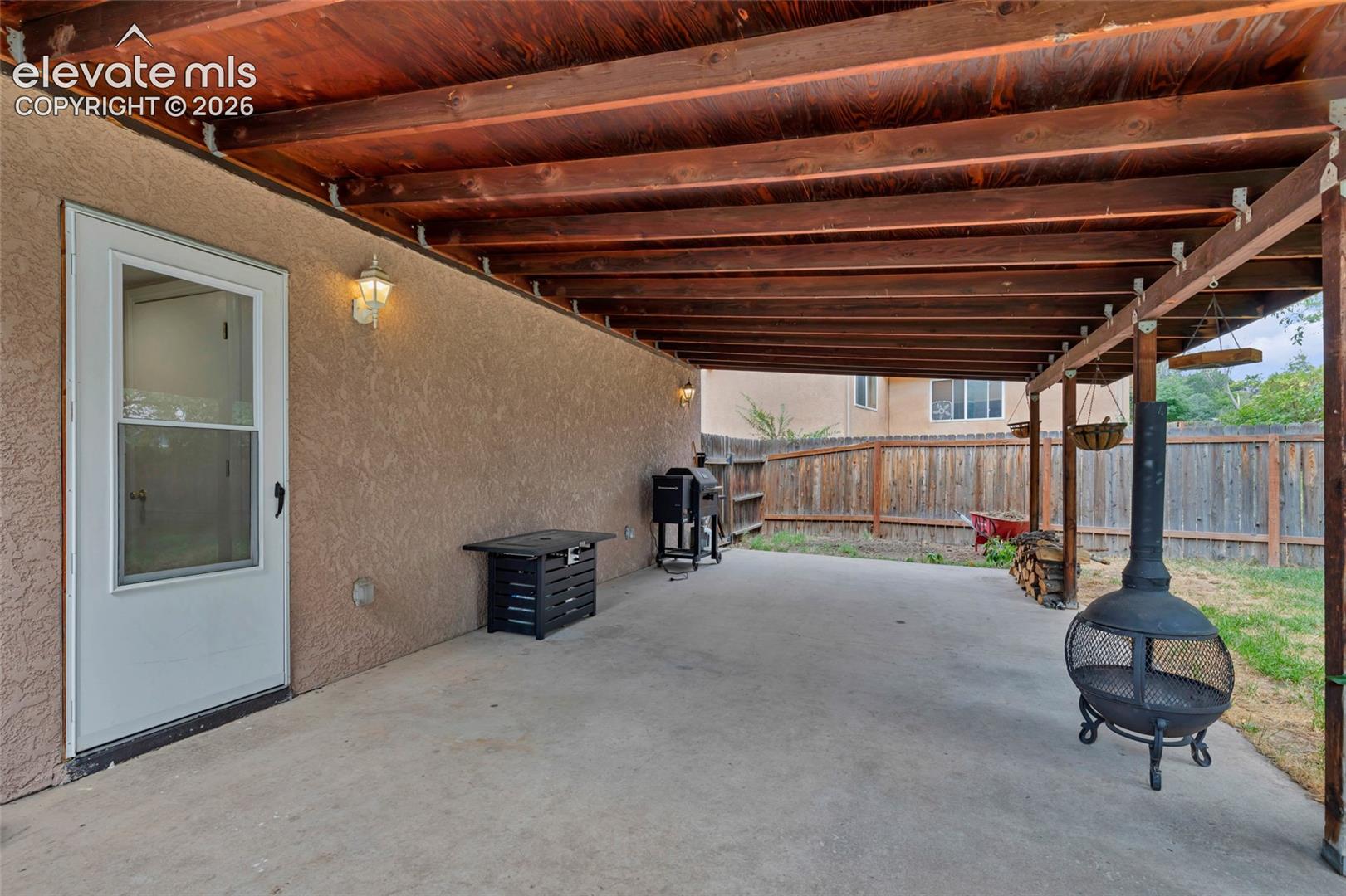 Covered patio with a concrete surface and exposed wood beam ceiling