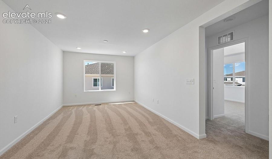 Neutral-toned carpeted flooring, recessed lighting, and large windows featuring a multi-paned exterior design