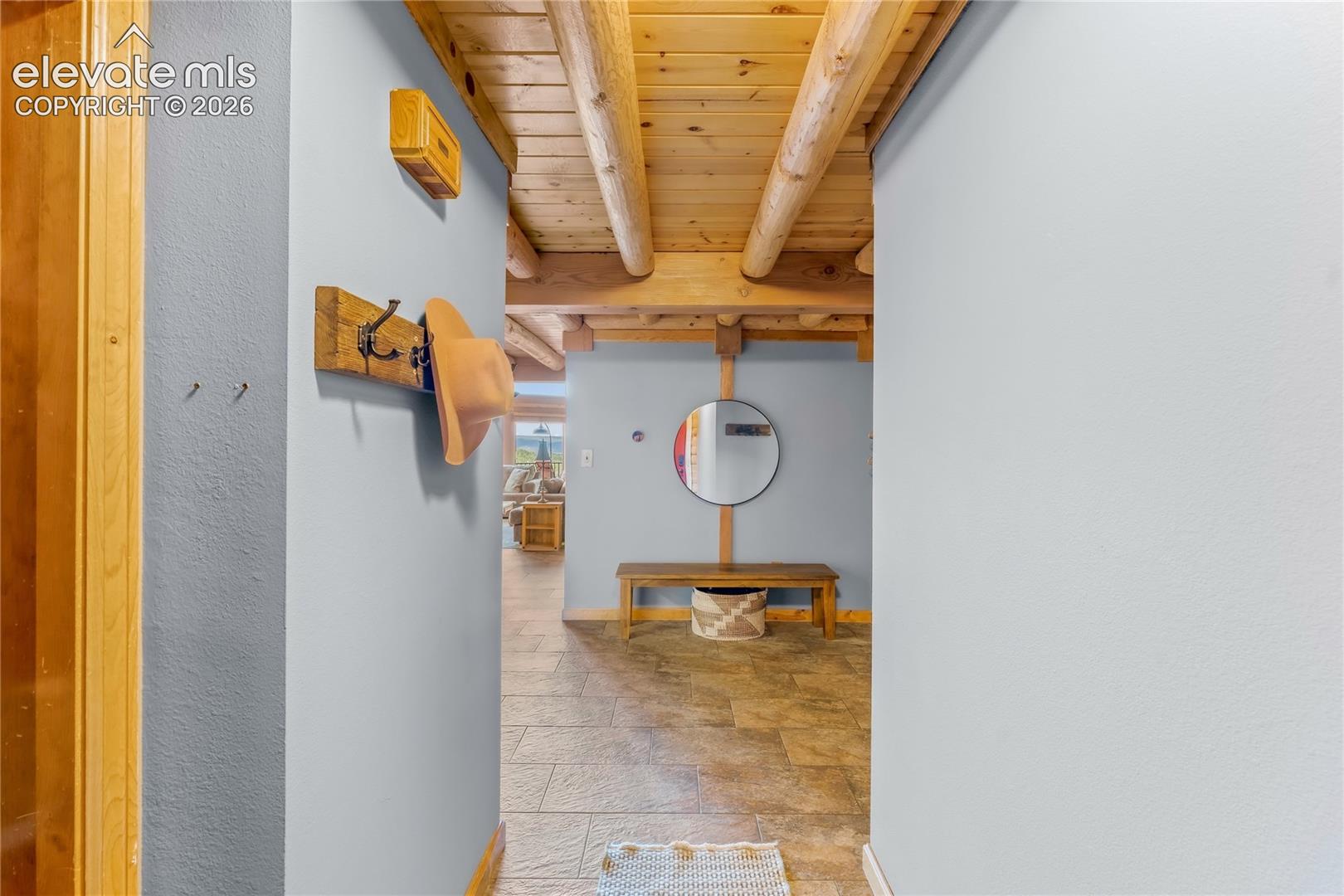 Rustic exposed wood beam ceiling above tile flooring