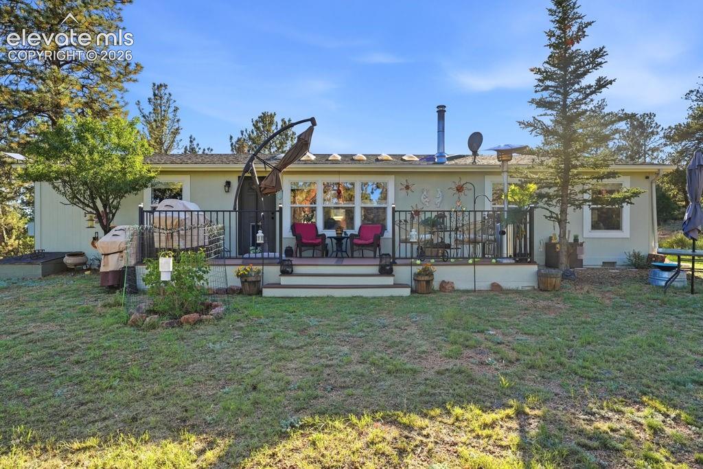 Rear deck with exterior railings, multiple windows, and exterior sconce lighting