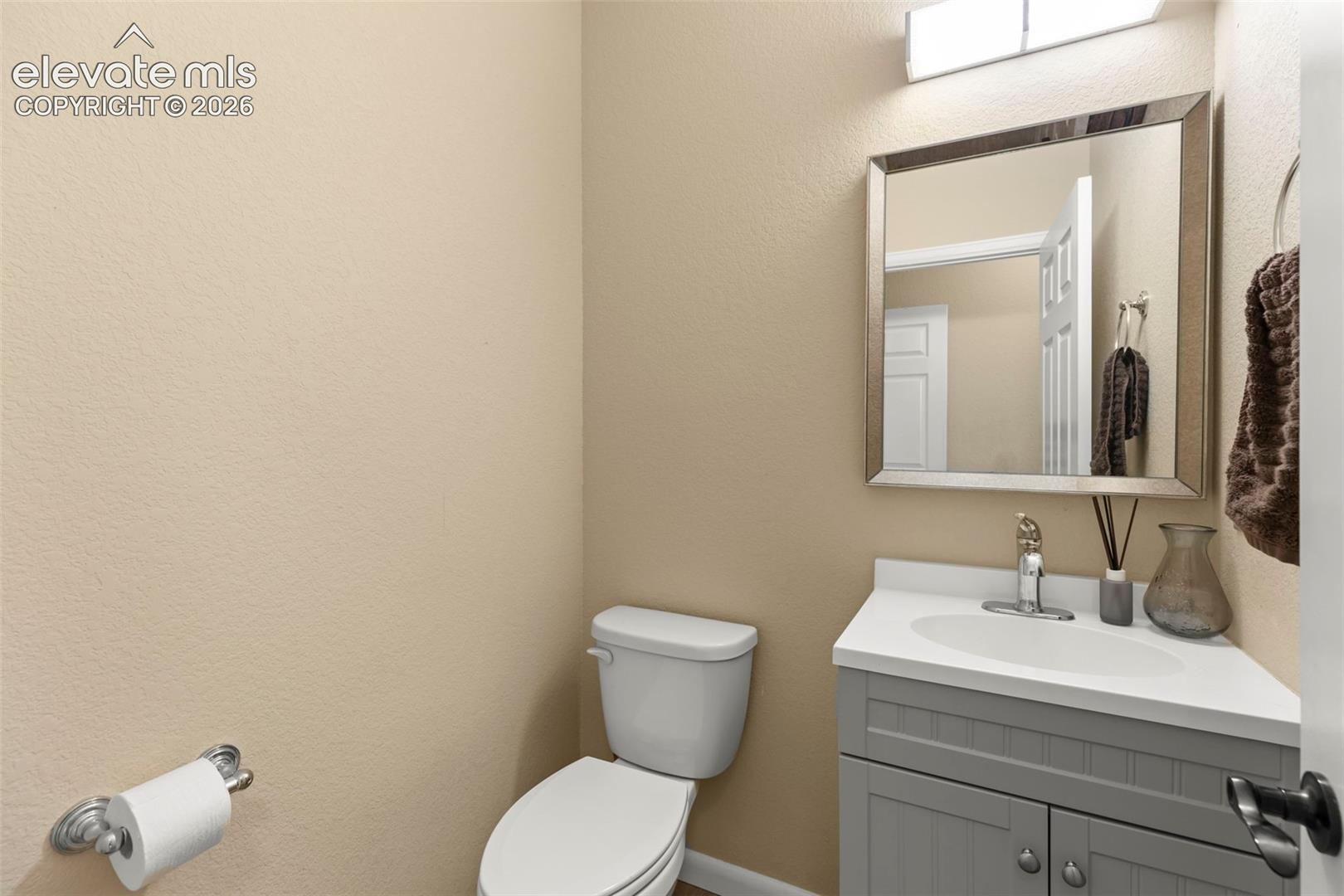 Gray vanity with beadboard detailing, integrated sink, solid surface countertop, polished chrome faucet, and rectangular framed wall mirror