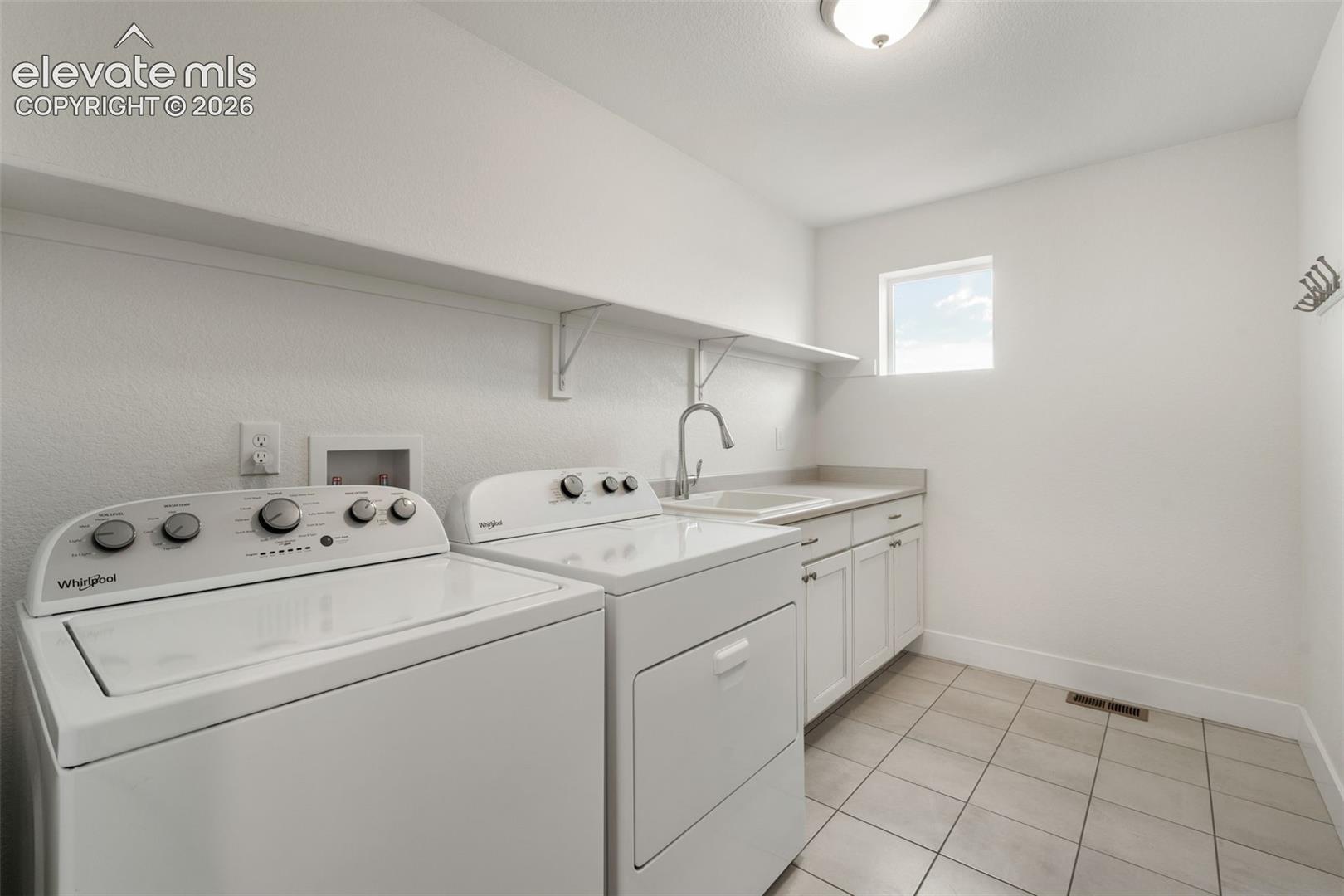 Laundry room featuring white shaker cabinetry, an integrated utility sink, a wall-mounted faucet, and tiled flooring