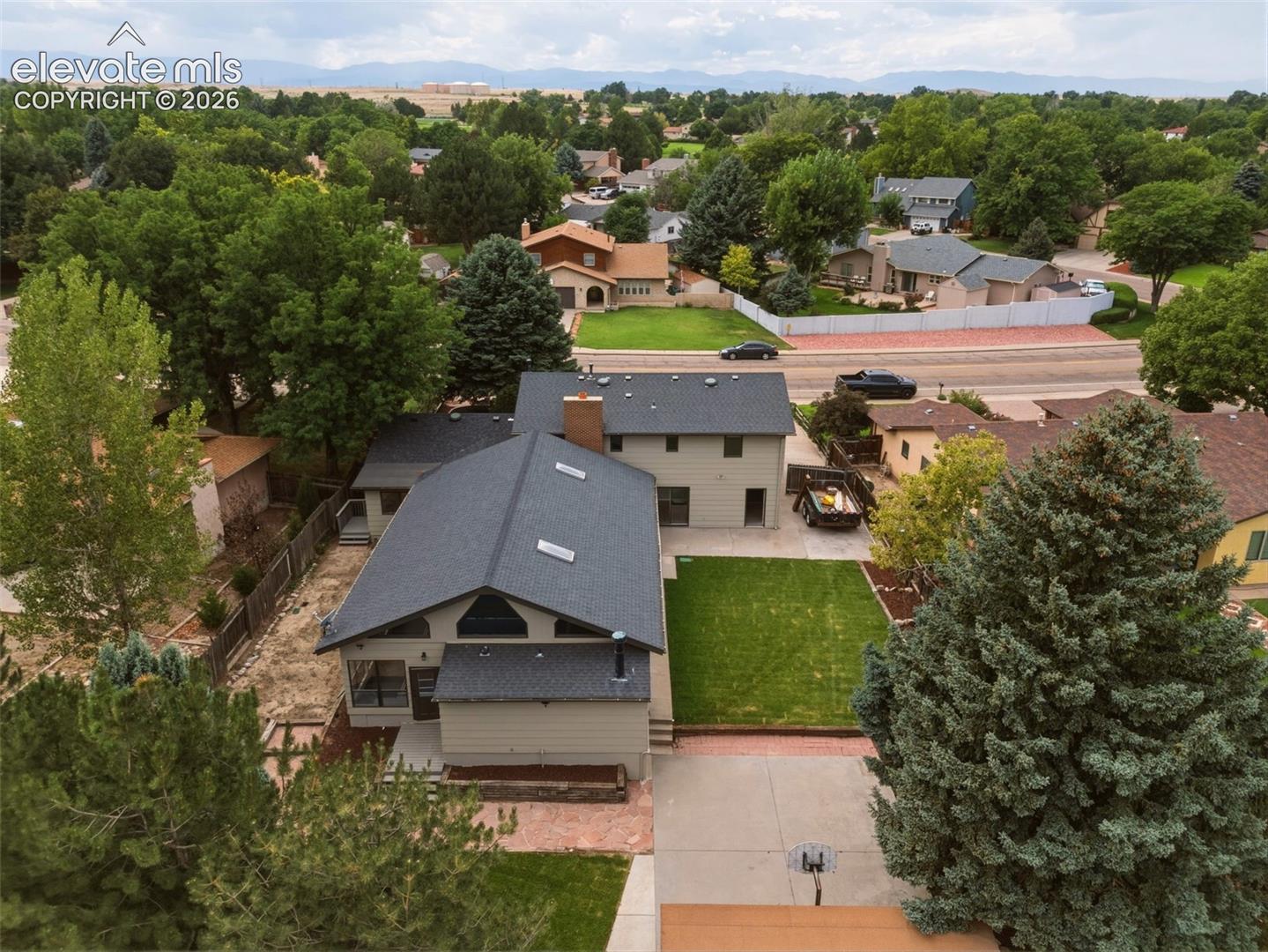 Dual-level residence featuring a dark shingle roof, neutral-toned siding, and a red brick chimney