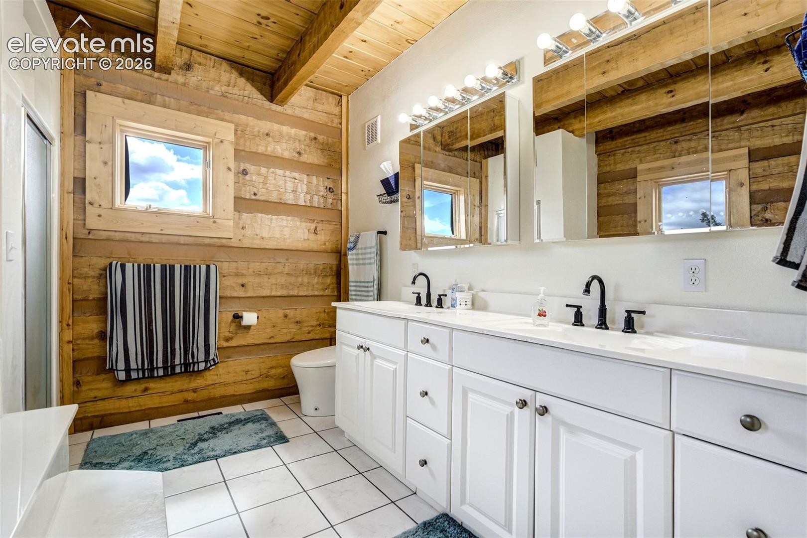 Bathroom featuring wood-paneled walls and a wooden beamed ceiling