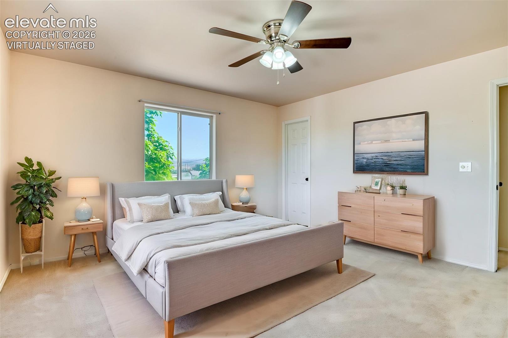 Neutral wall color, ceiling fan with light kit, and natural light provided by a single-panel window Virtually staged