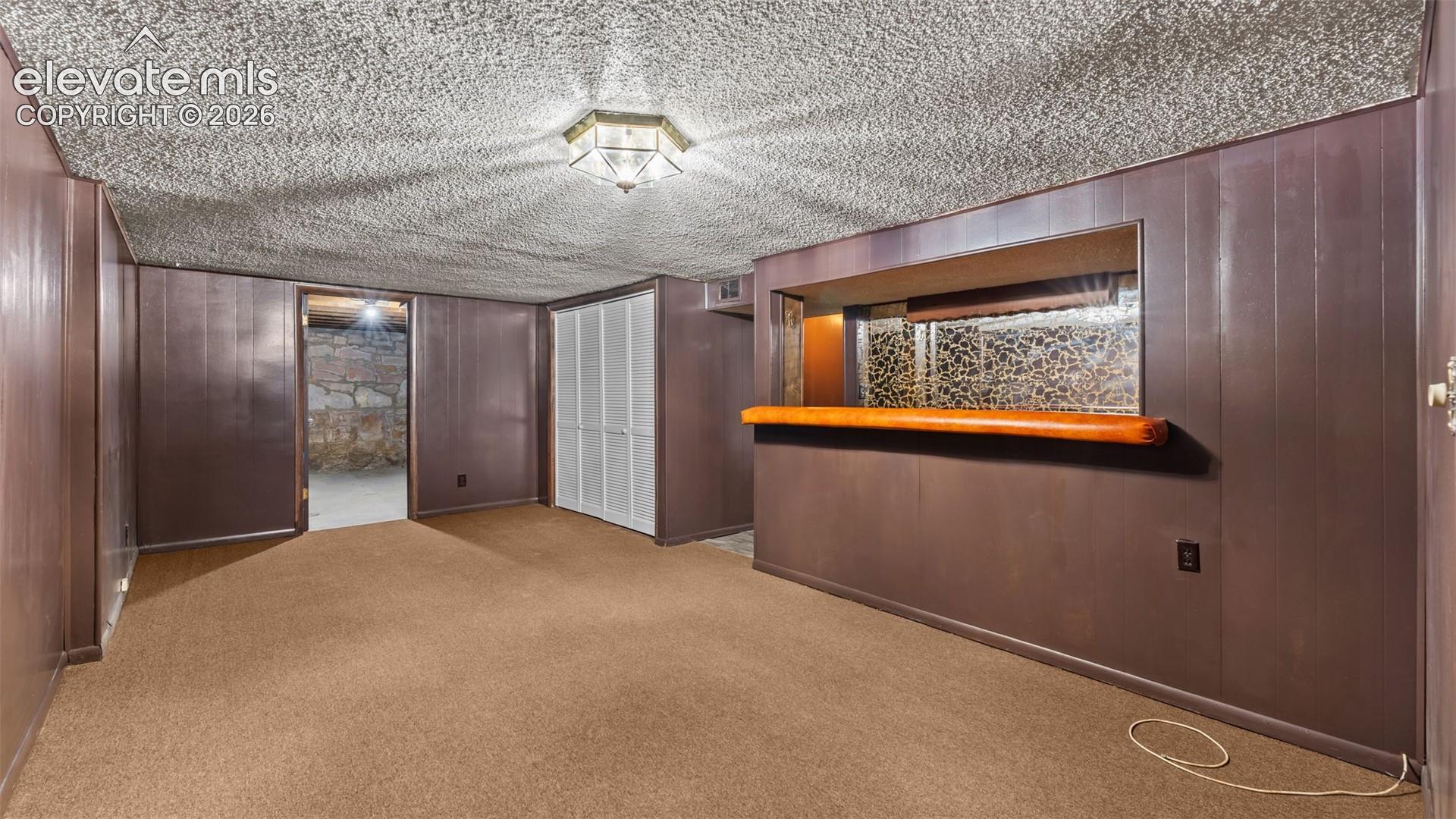 Spacious finished basement with wood-finish flooring, wood-paneled walls, and recessed ceiling lighting