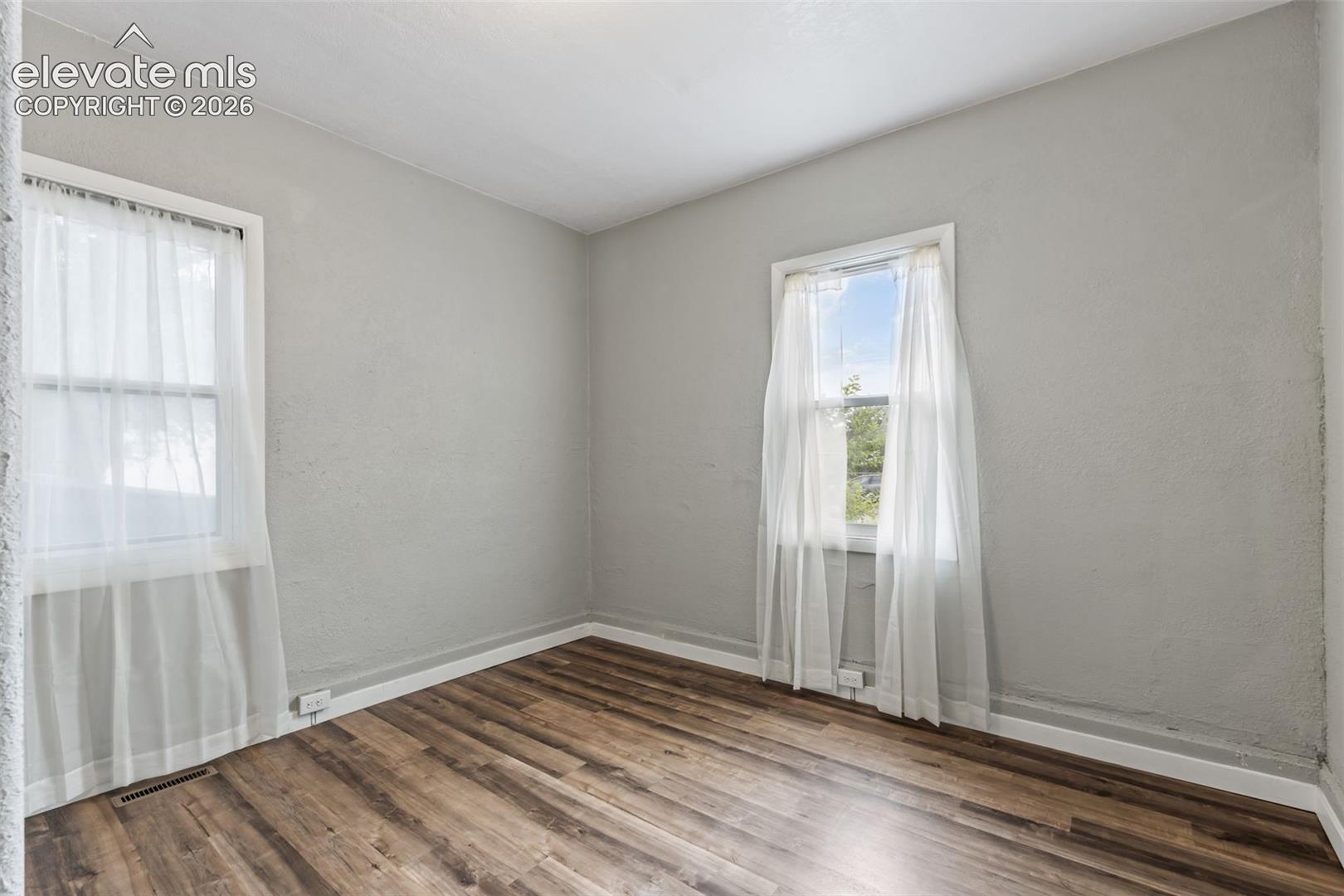 Room featuring wood-finish flooring, light gray wall paint, and white trim