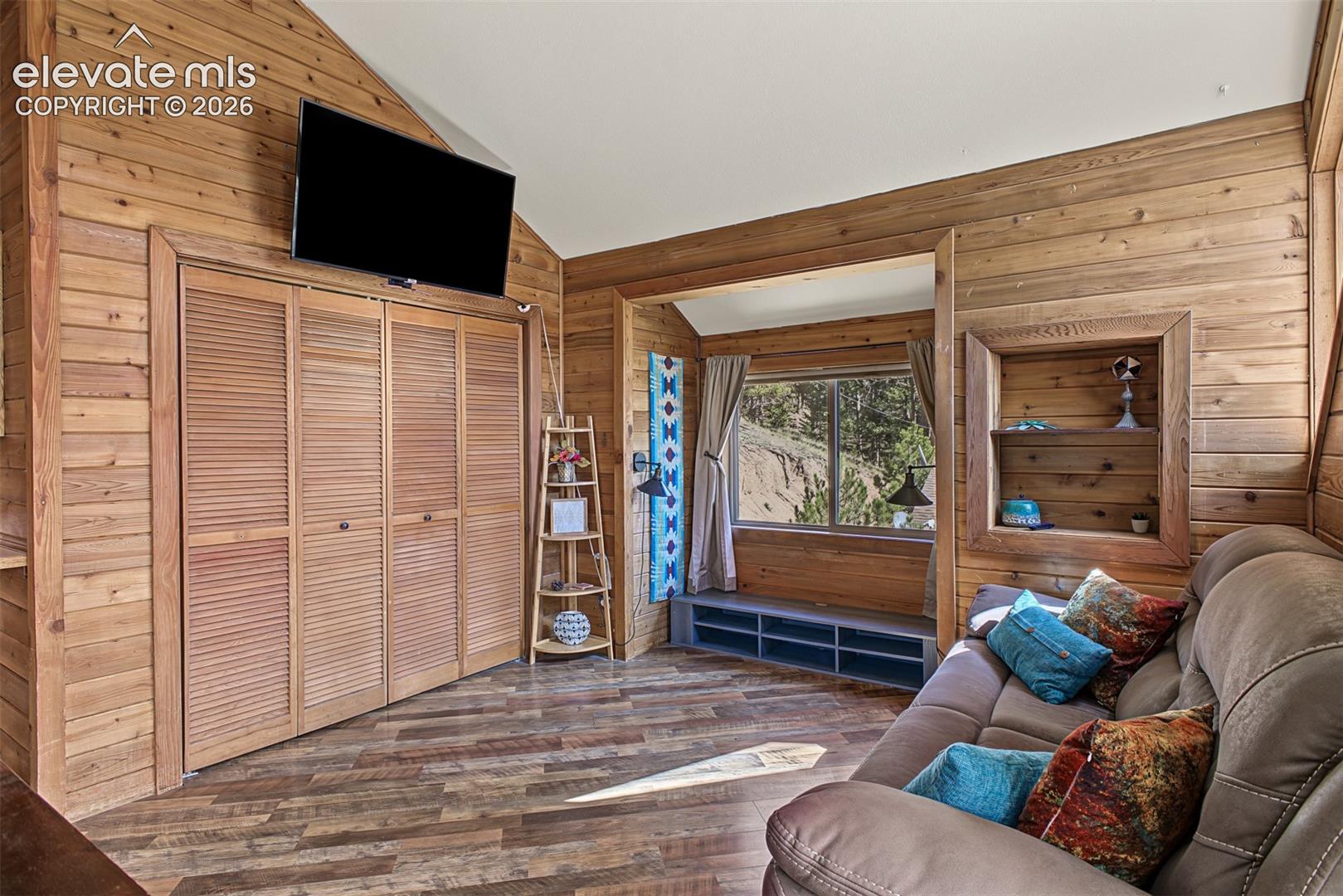 Wood-paneled interior walls, angled ceiling, built-in storage niche, louvered bi-fold closet doors, wood-finish flooring