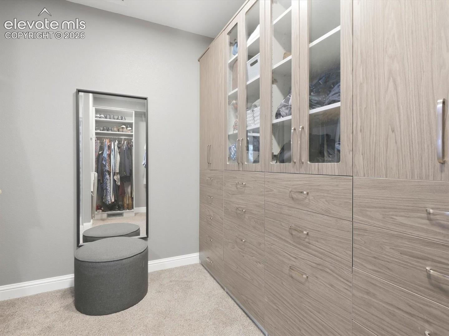 Primary Built-in storage cabinetry featuring wood-finish cabinetry, glass-front upper doors, and integrated pull-out drawers with metallic hardware
