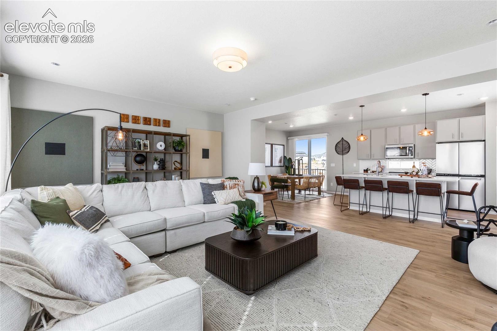 Open-concept living space featuring wood-finish flooring, recessed lighting, and a kitchen with an island, pendant lights, and stainless steel appliances
*photos of a model home*