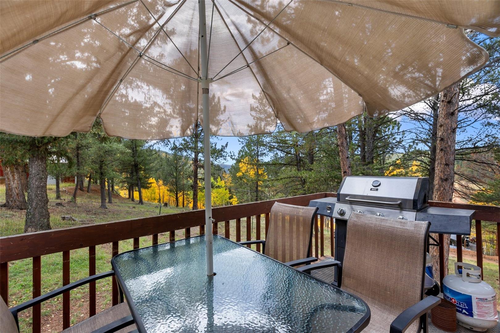Outdoor deck with wood railings, integrated gas grill, and glass-top table