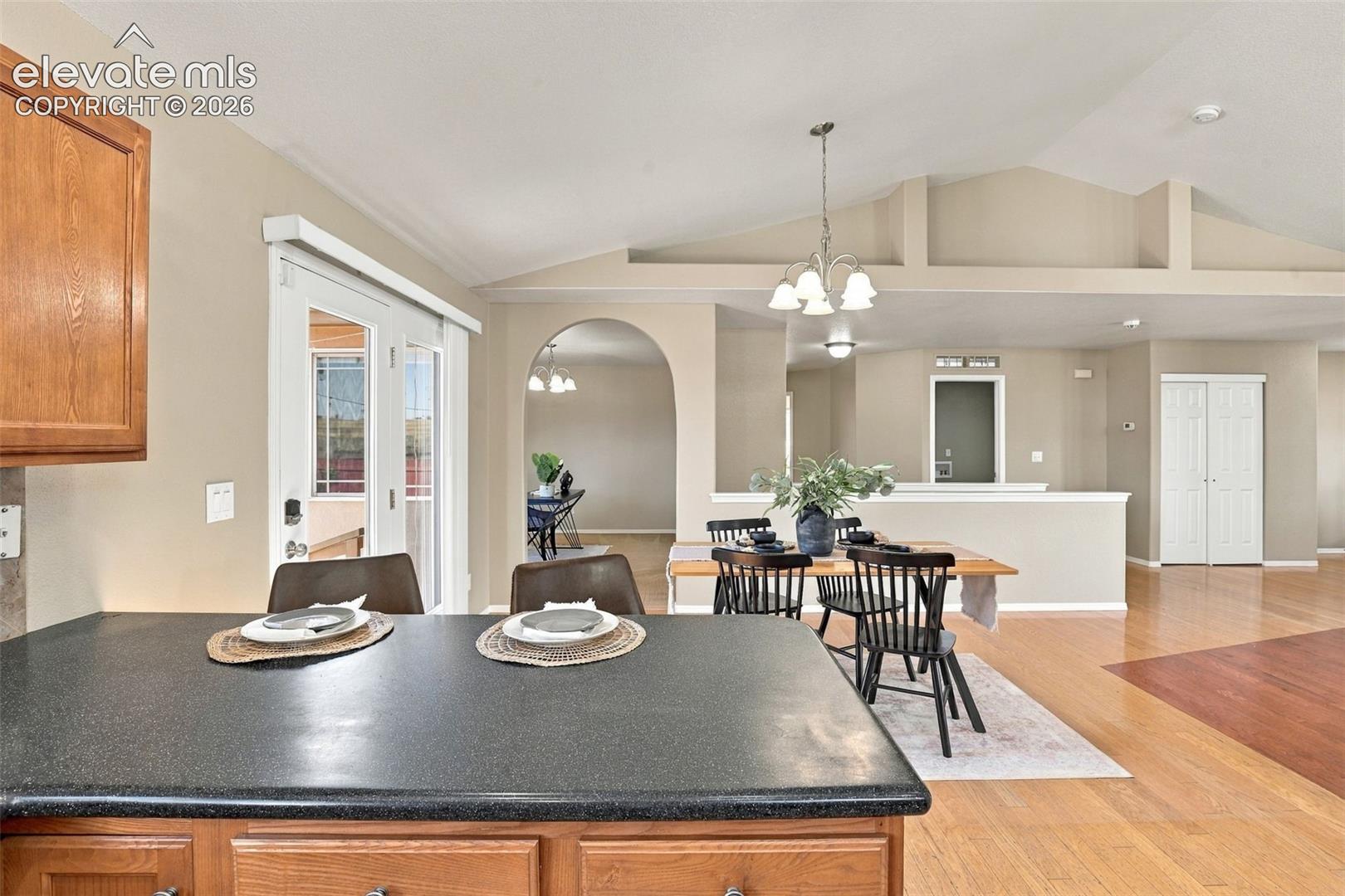 Vaulted ceilings, wood-finish flooring, archway, and built-in bifold closet doors