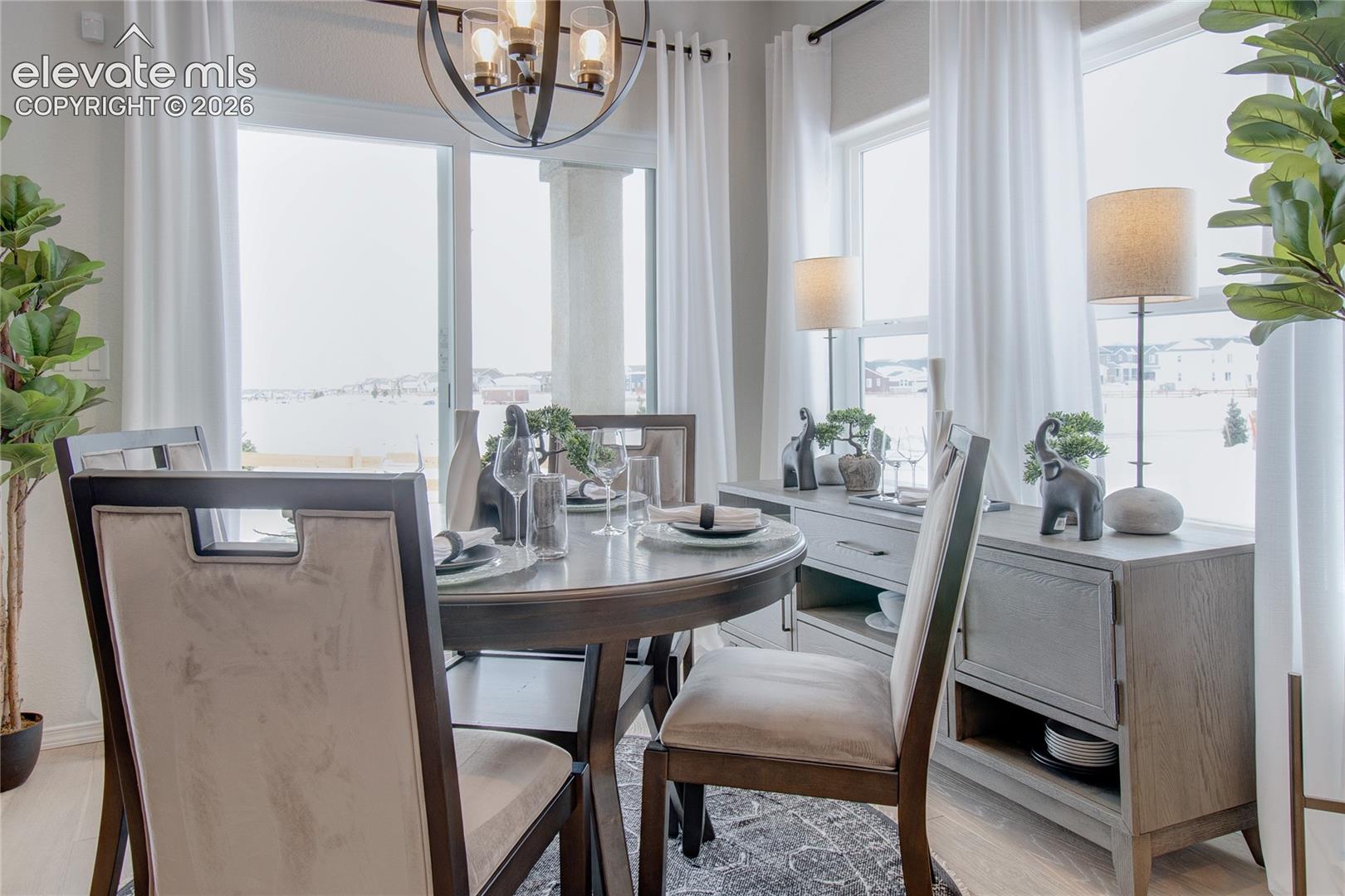 Dining space featuring large windows, sliding glass door, spherical iron chandelier, and light-toned flooring