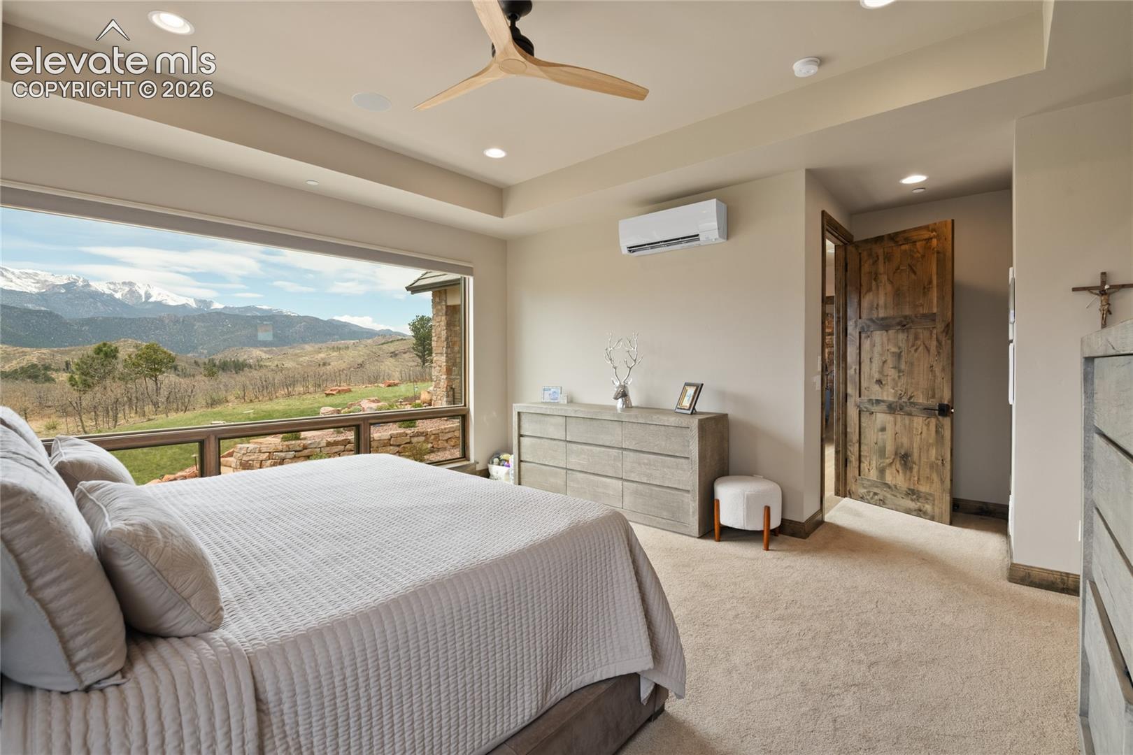 The view that earns its rest. Spacious primary retreat featuring a recessed ceiling detail, oversized picture window framing Pikes Peak, dedicated mini-split system for personalized comfort, and direct ensuite access.