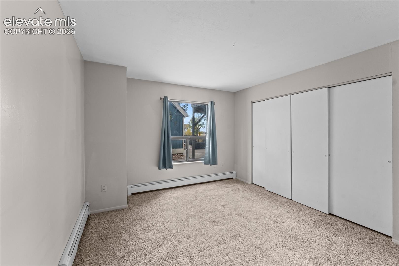 Interior room featuring neutral wall paint, carpeted flooring, and a sliding-door closet