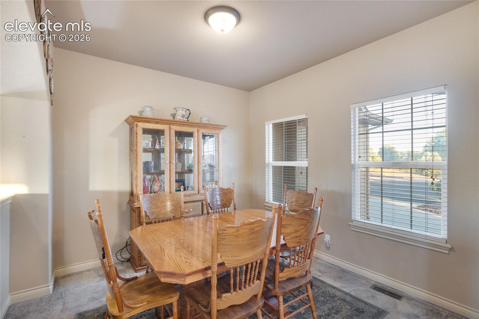 Dining area featuring neutral wall paint, dual windows with horizontal blinds, and a flush-mount ceiling light fixture