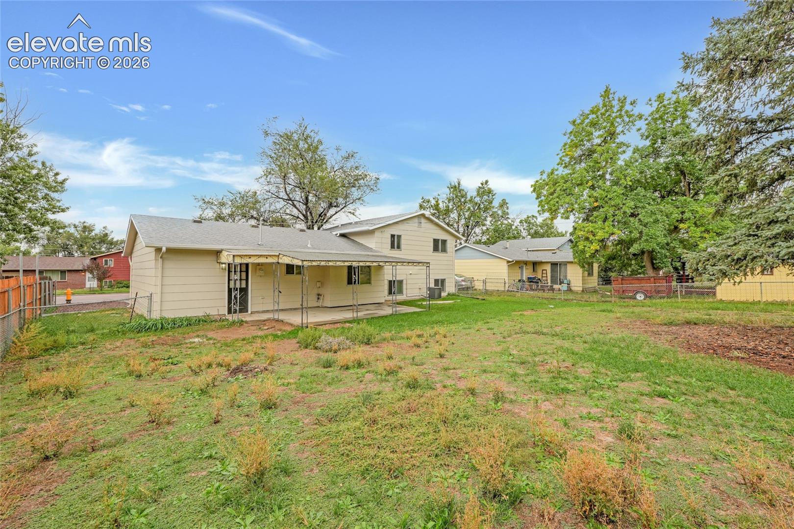 Expansive rear yard with a fenced perimeter and mature trees